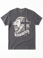 A dark gray crewneck t-shirt featuring a graphic print of a roaring lion and a cross, with a banner below reading 'MAN OF FAITH' in white text, shown flat against a white background.