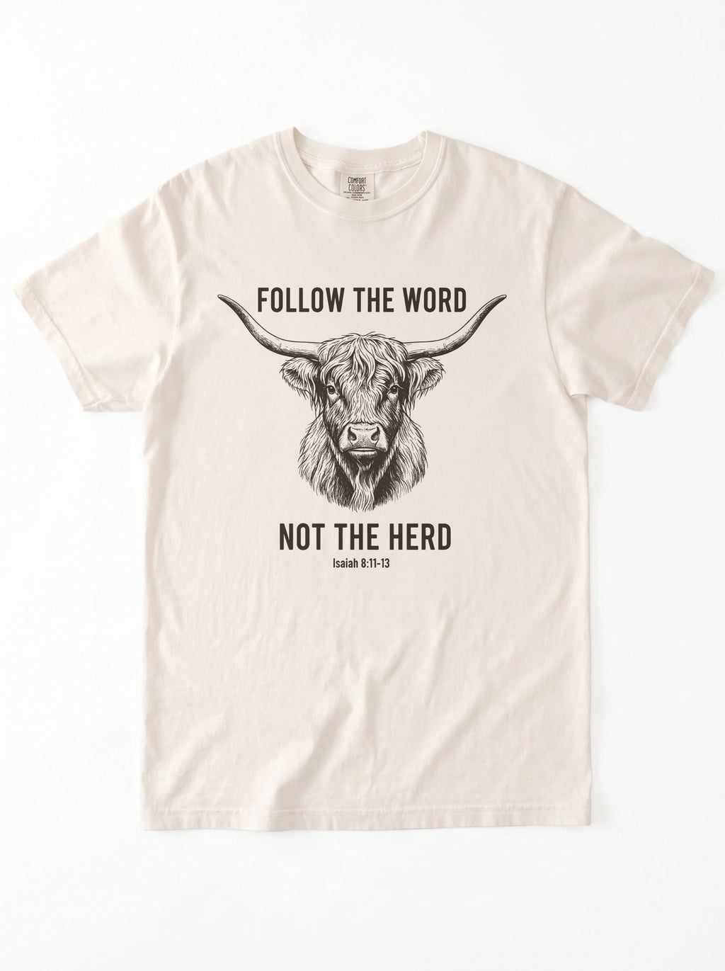 An off-white short-sleeve crewneck t-shirt featuring a black graphic of a highland cow and the text 'FOLLOW THE WORD NOT THE HERD' and 'Isaiah 8:11-13'.