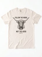 An off-white short-sleeve crewneck t-shirt featuring a black graphic of a highland cow and the text 'FOLLOW THE WORD NOT THE HERD' and 'Isaiah 8:11-13'.