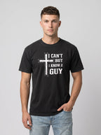 A man wearing a black crewneck t-shirt with a white distressed graphic of a cross and the text 'I CAN'T BUT I KNOW A GUY'.