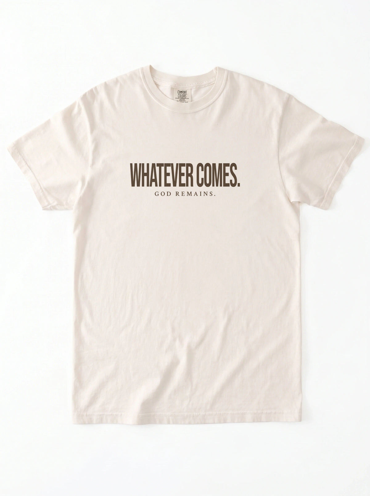 A light beige crewneck t-shirt with the text 'WHATEVER COMES. GOD REMAINS.