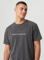 Man wearing dark gray Comfort Colors t-shirt with cross and Trust His Plan Jeremiah 29:11 design on front