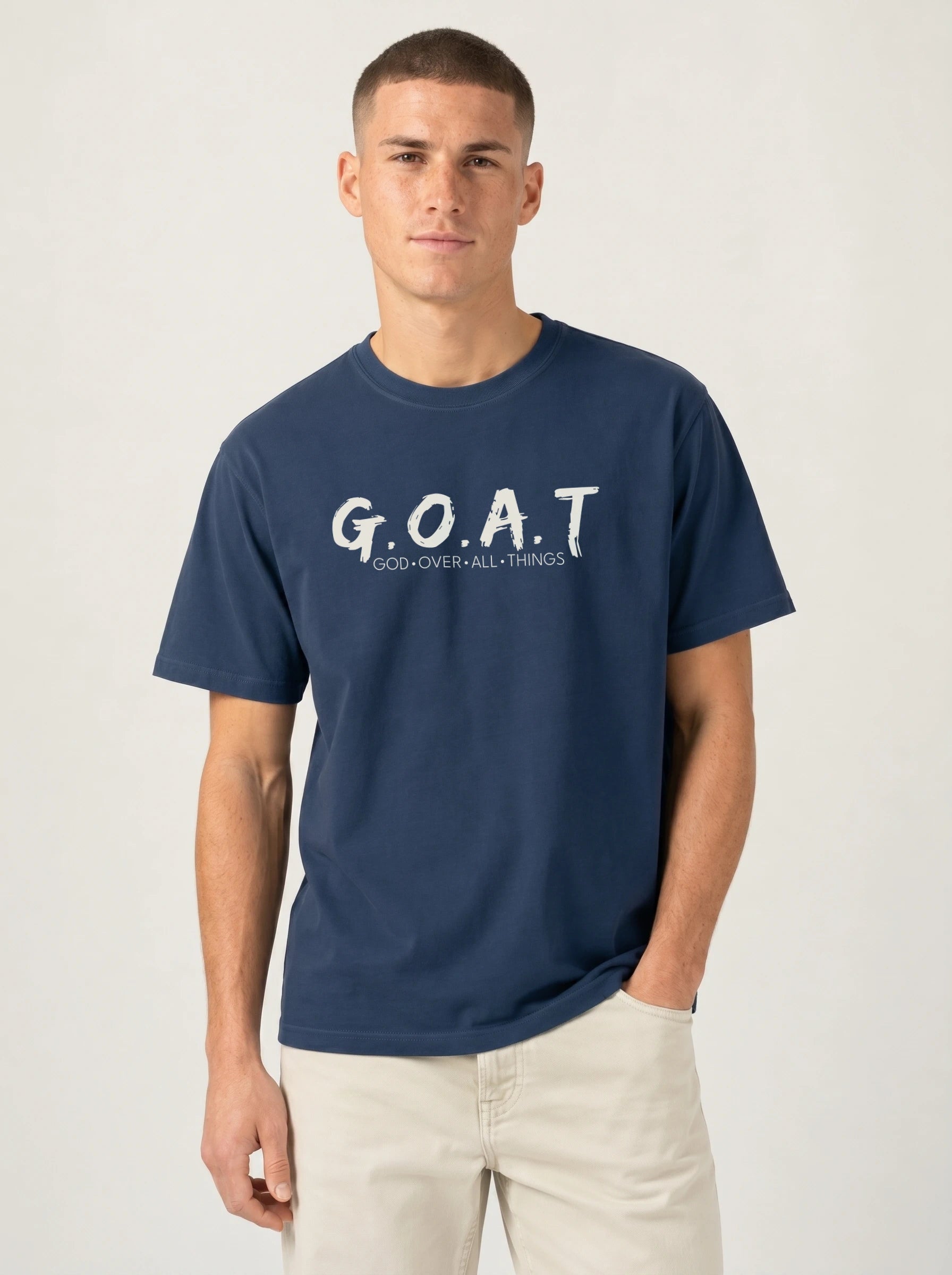 A man wearing a navy blue t-shirt with ''G.O.A.T GOD OVER ALL THINGS' print across the chest.