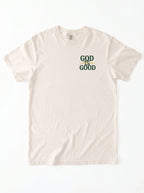 An off-white short-sleeve t-shirt with a graphic on the left chest that reads 'GOD IS GOOD' in dark green and yellow.
