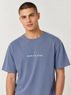 Person wearing a faded blue T-shirt with a small cross above the text “Man of God.”