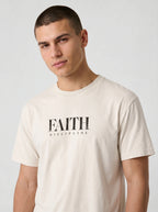 Person wearing a cream T-shirt with distressed black text reading “FAITH” and “DISCIPLINE.”