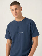 Person wearing a navy blue T-shirt with a white cross above the text “Jesus is King.”