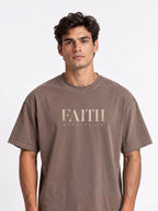 Person wearing a faded brown T-shirt with distressed beige text reading “FAITH” and “DISCIPLINE.”