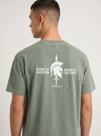 A man wearing a sage green t-shirt, viewed from the back. The shirt features a white graphic print of a Spartan helmet and sword with the text 'HELMET OF SALVATION' and 'SWORD OF THE SPIRIT' and 'ESPHANSAS 6:17'.