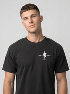 A man wearing a black crewneck t-shirt with a white graphic on the left chest depicting a graphic print of a Spartan helmet and sword with the text 'HELMET OF SALVATION' and 'SWORD OF THE SPIRIT'.