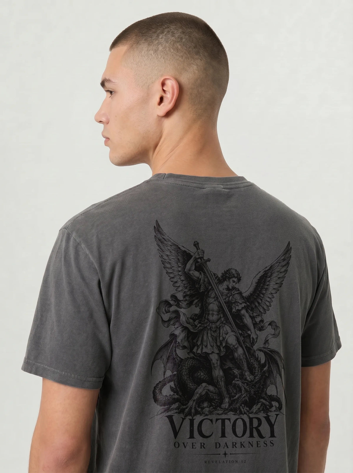 Charcoal T-shirt with a winged warrior defeating a dragon and the text “VICTORY OVER DARKNESS” and “REVELATION 12.”