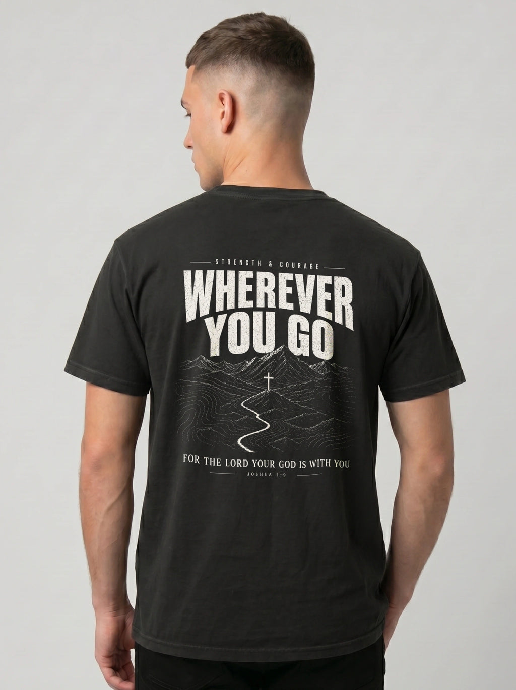 A man viewed from the back wearing a black t-shirt with a large white graphic print on the back that reads 'WHEREVER YOU GO' and 'FOR THE LORD YOUR GOD IS WITH YOU'.