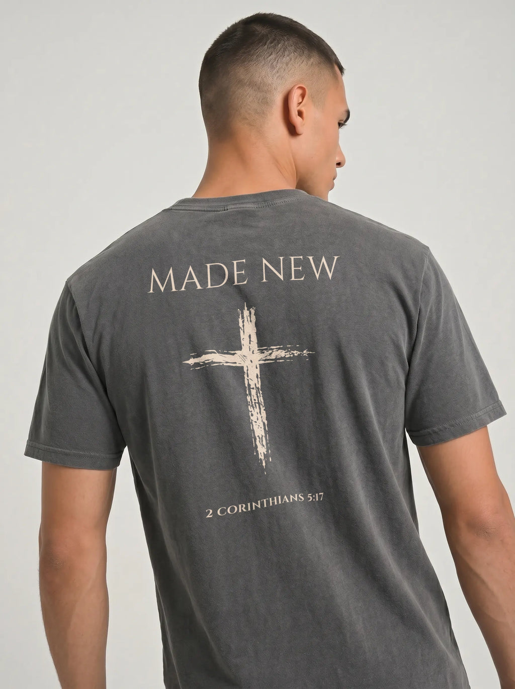 Close-up back view of dark gray Comfort Colors tee with distressed cross, Made New text, and 2 Corinthians 5:17 verse