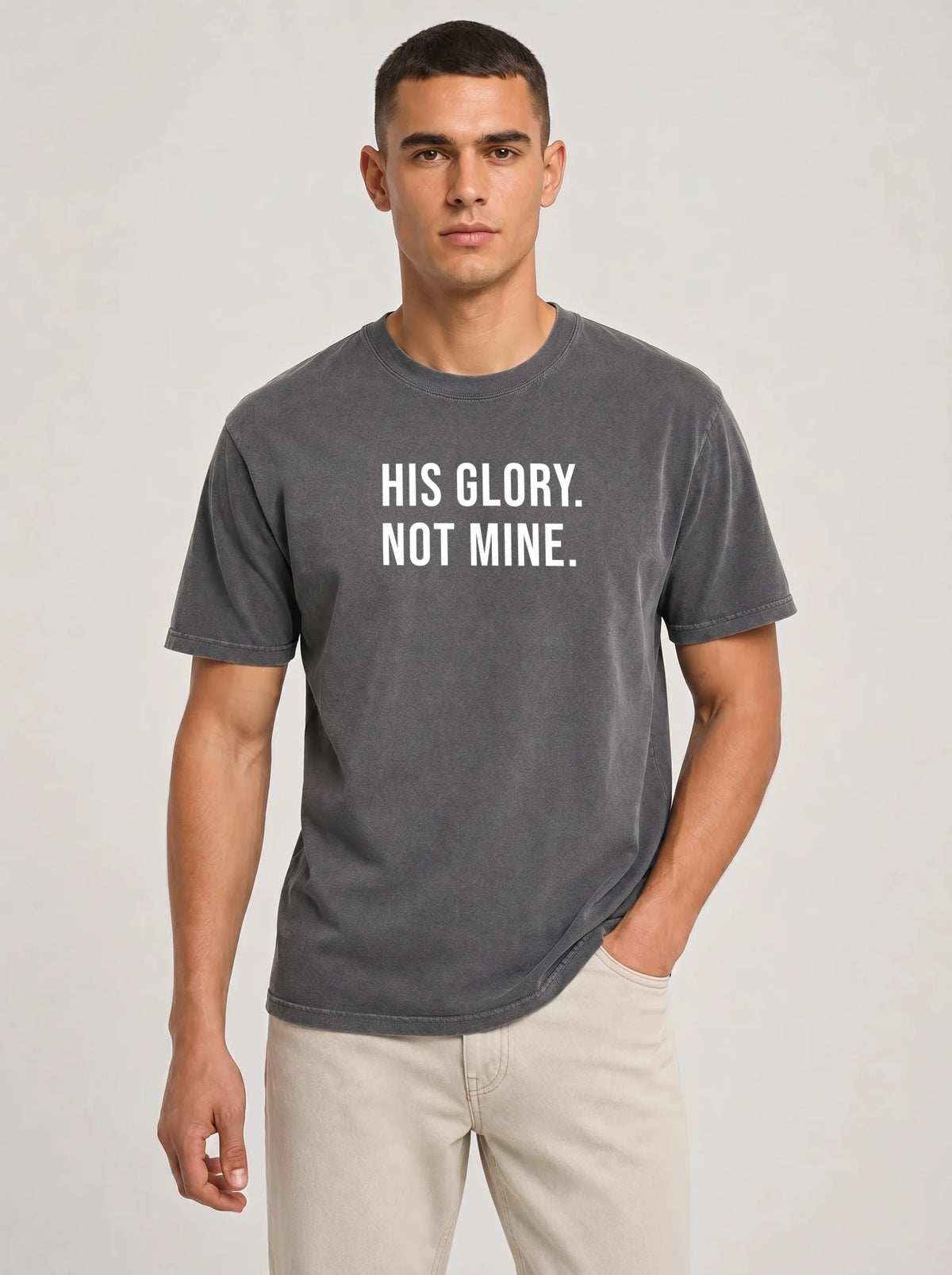Man wearing a charcoal gray Comfort Colors garment-dyed t-shirt printed with 'His Glory. Not Mine.' Christian faith quote