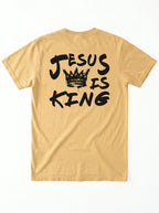 A tan short-sleeve t-shirt shown from the back, featuring a black graphic print that reads 'JESUS IS KING' with a crown illustration in the center, laid flat against a white background.