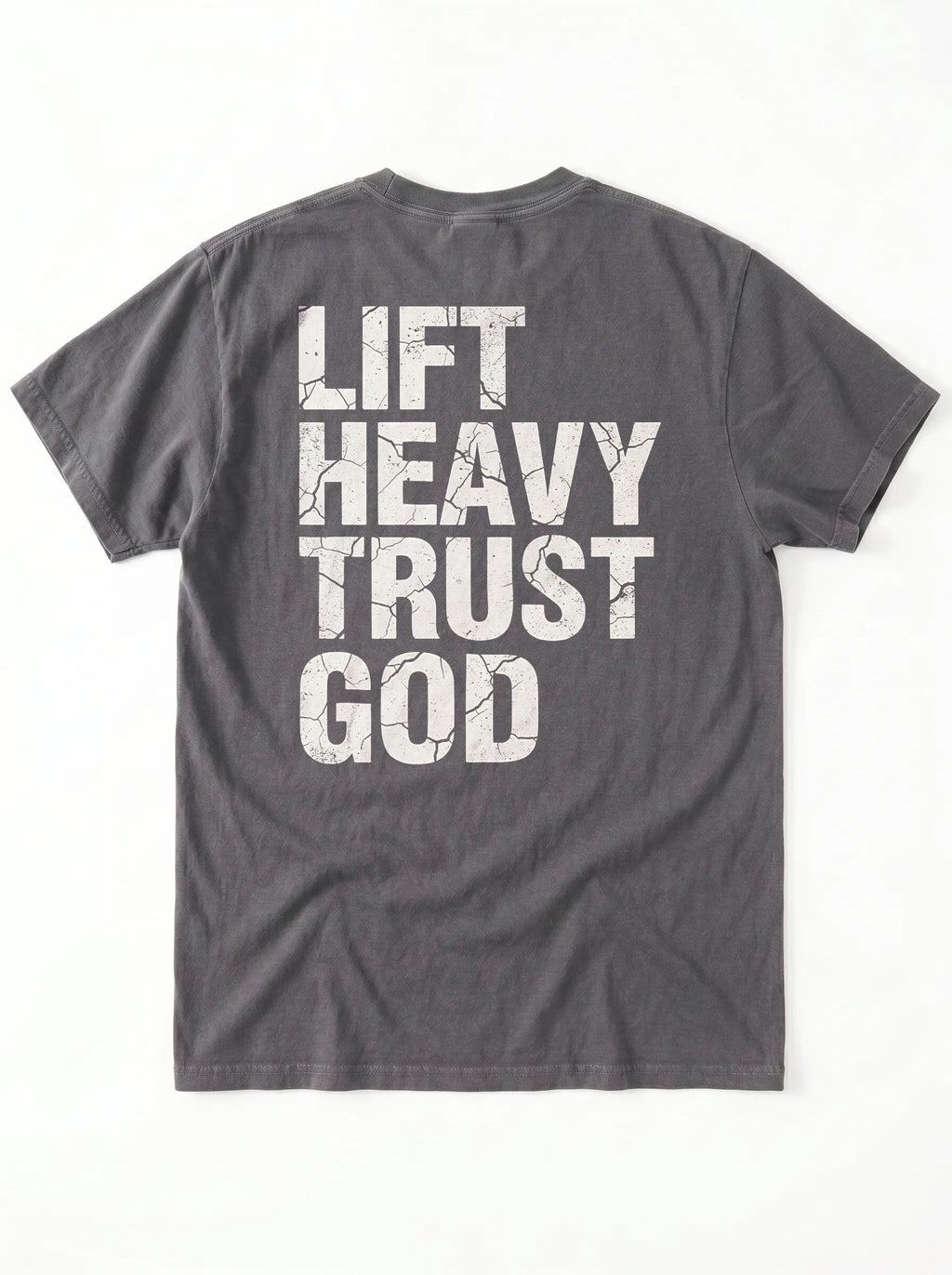 A dark gray crewneck t-shirt shown from the back, featuring the phrase 'LIFT HEAVY TRUST GOD' printed in large, distressed white block letters.