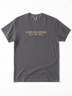 Charcoal grey “God Is Good All The Time” Christian graphic T-shirt laid flat on white background.