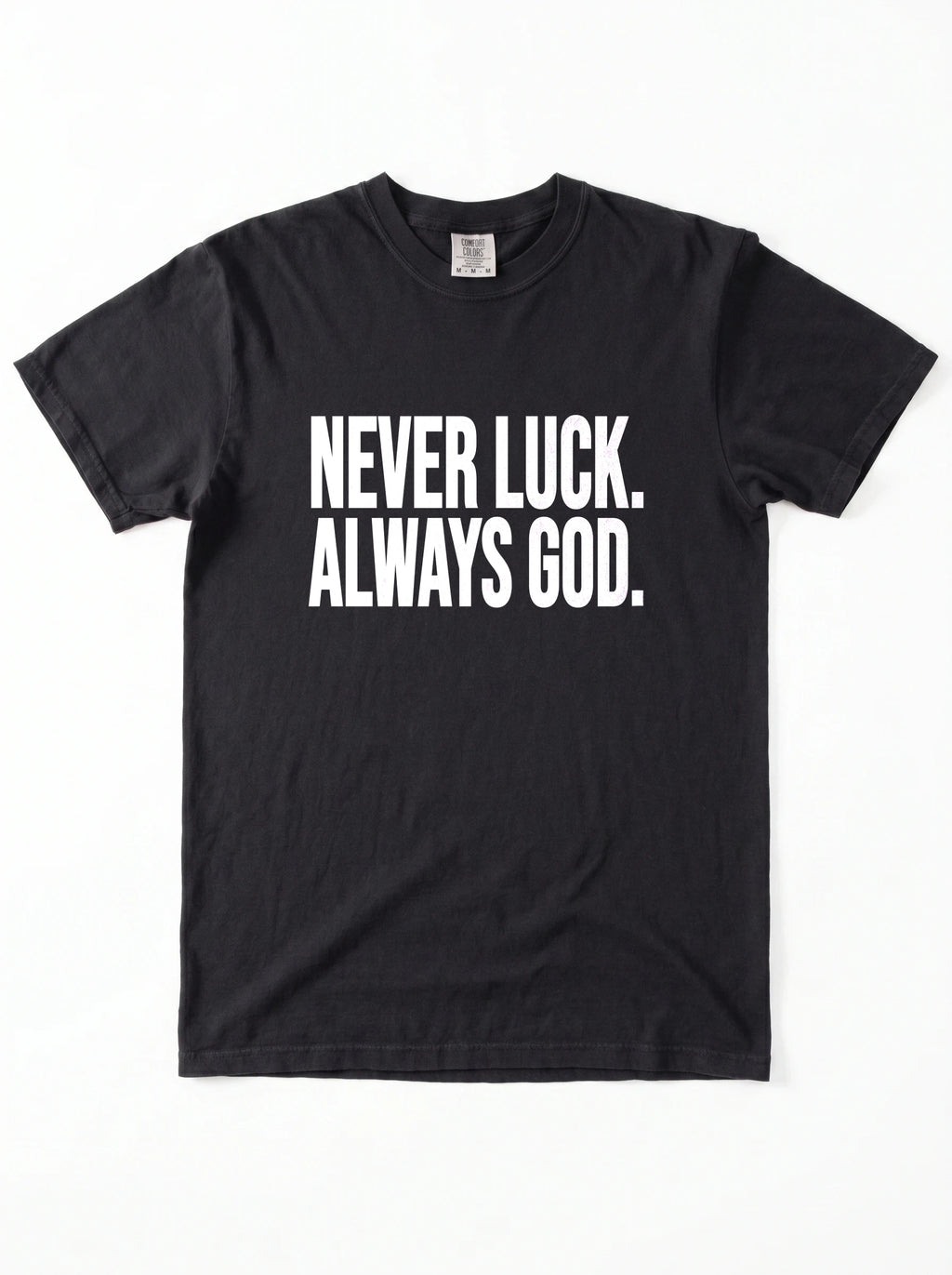 Black T-shirt laid flat with white text reading “Never luck. Always God.”