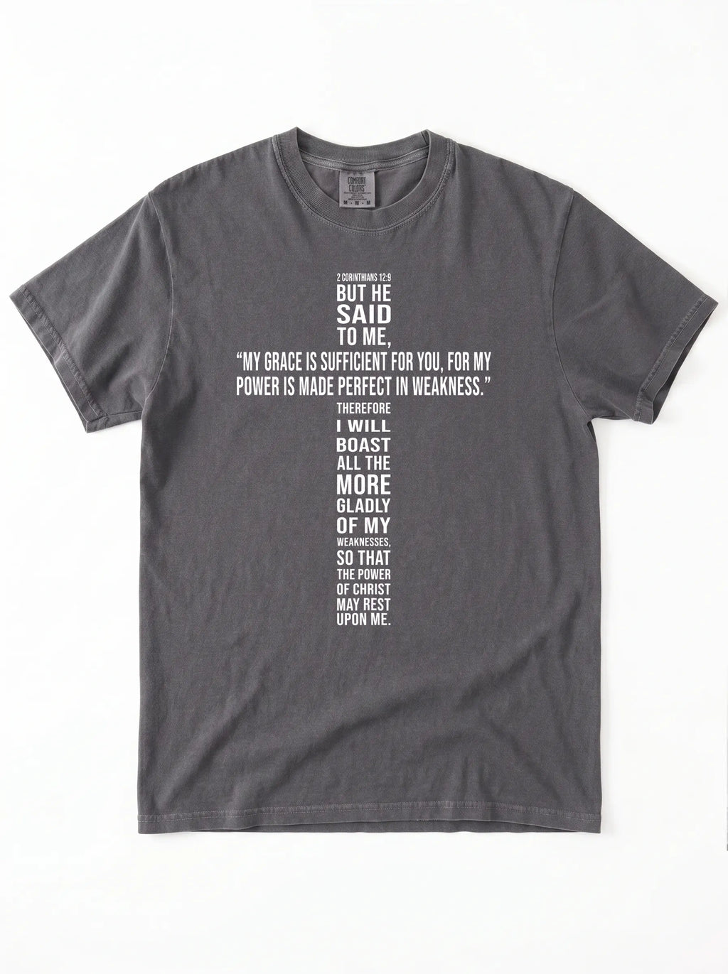Washed charcoal-gray T-shirt laid flat with white text quoting 2 Corinthians 12:9: “My grace is sufficient for you, for my power is made perfect in weakness.”