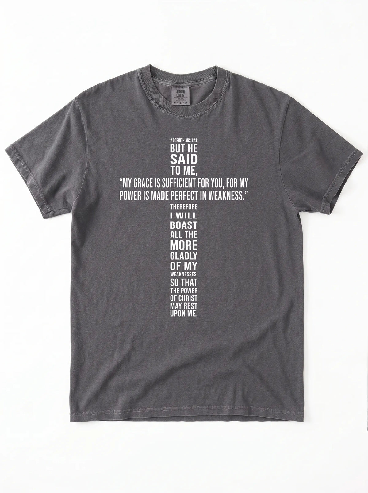 Washed charcoal-gray T-shirt laid flat with white text quoting 2 Corinthians 12:9: “My grace is sufficient for you, for my power is made perfect in weakness.”