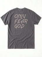 A dark gray t-shirt shown from the back, featuring the phrase 'ONLY FEAR GOD' printed in a light beige stylized font.