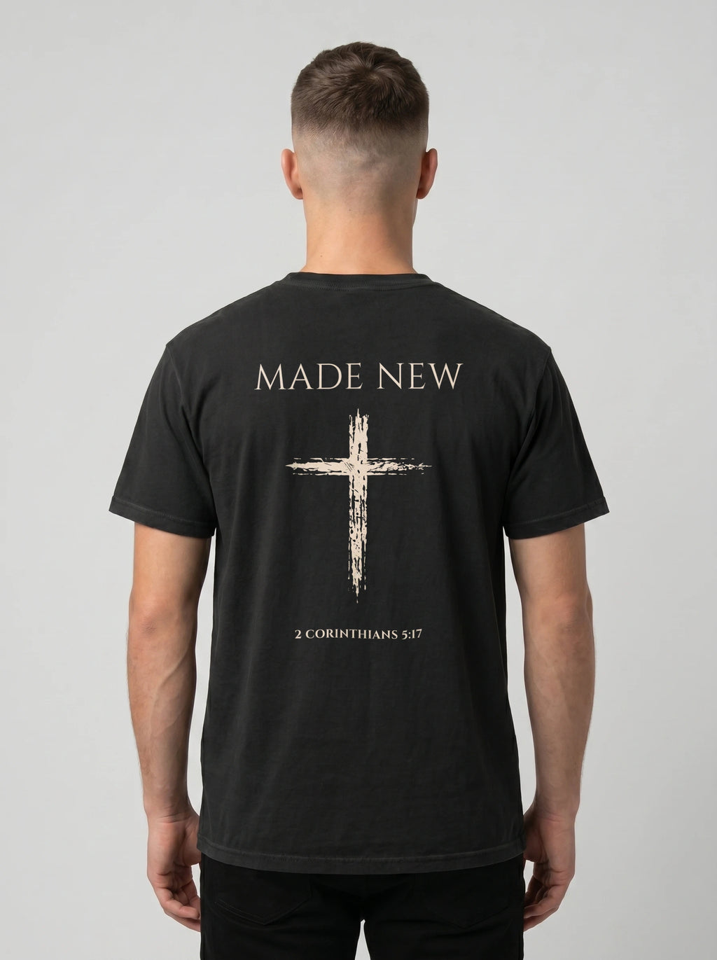 Man wearing black Comfort Colors t-shirt with Made New cross graphic and 2 Corinthians 5:17 verse on back