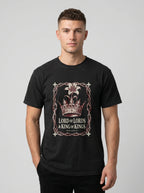 A man wearing a black crewneck t-shirt with a graphic print of a crown and the text 'LORD of LORDS & KING of KINGS' on the front, set against a plain light gray background.
