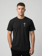 Man wearing black Comfort Colors t-shirt with small cross graphic on left chest