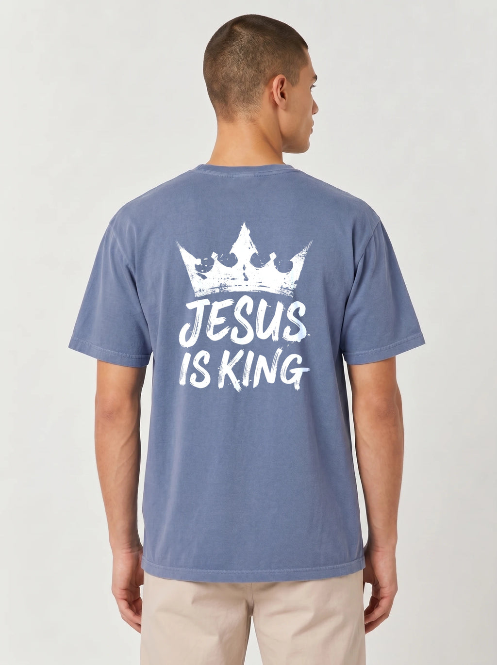 A man viewed from the back wearing a heathered blue t-shirt with a white graphic print of a crown and the text 'JESUS IS KING'.