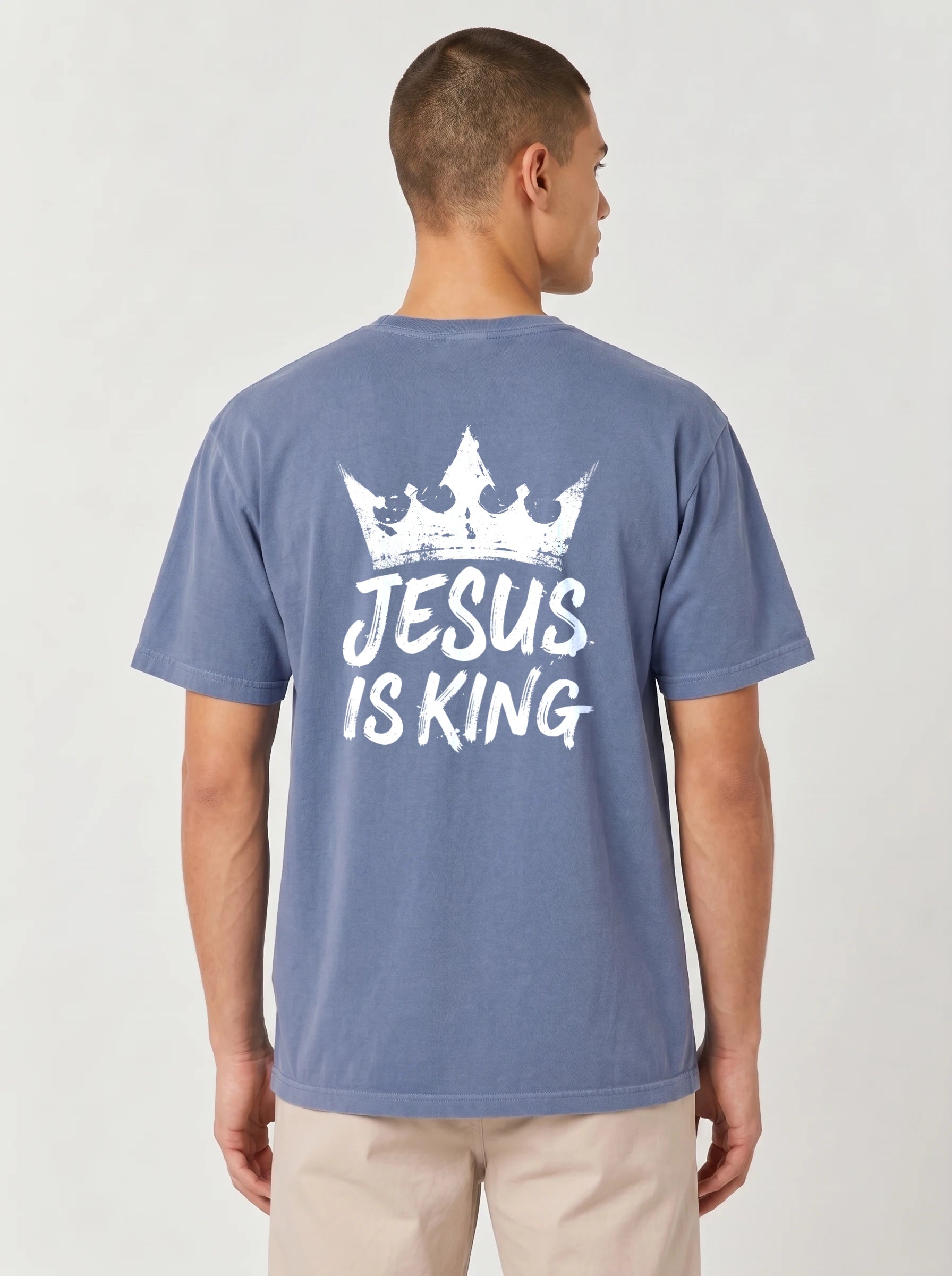 A man viewed from the back wearing a heathered blue t-shirt with a white graphic print of a crown and the text 'JESUS IS KING'.