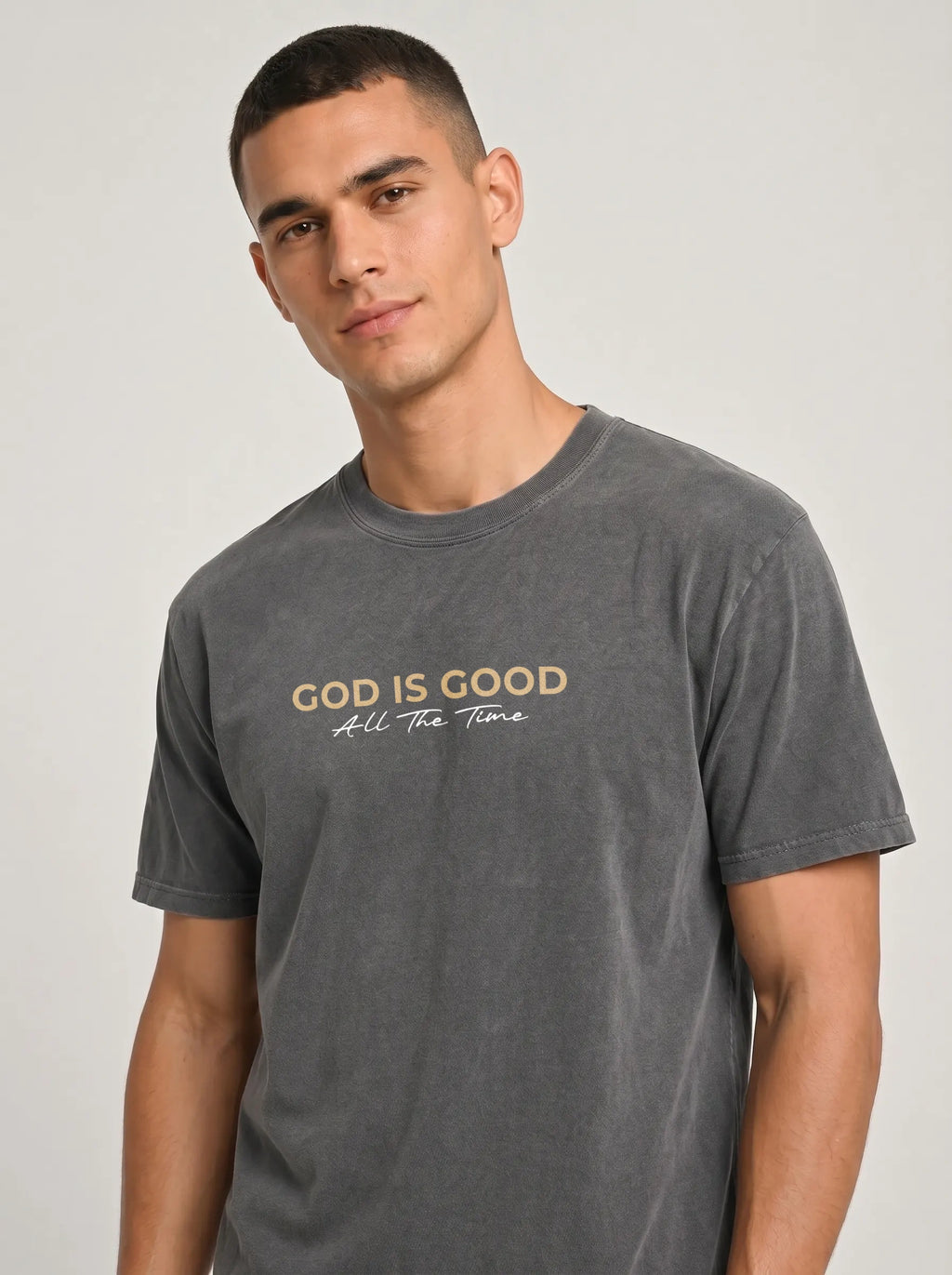 Close-up of man wearing charcoal grey “God Is Good All The Time” Christian graphic T-shirt.