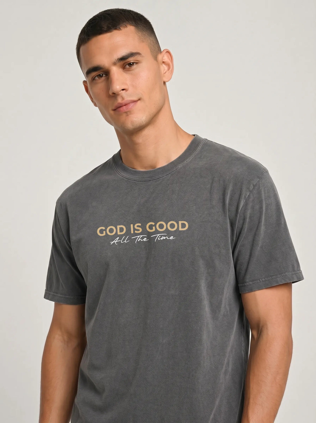Close-up of man wearing charcoal grey “God Is Good All The Time” Christian graphic T-shirt.
