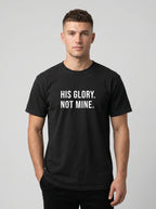 Man wearing a black Comfort Colors garment-dyed t-shirt printed with 'His Glory. Not Mine.' Christian faith quote
