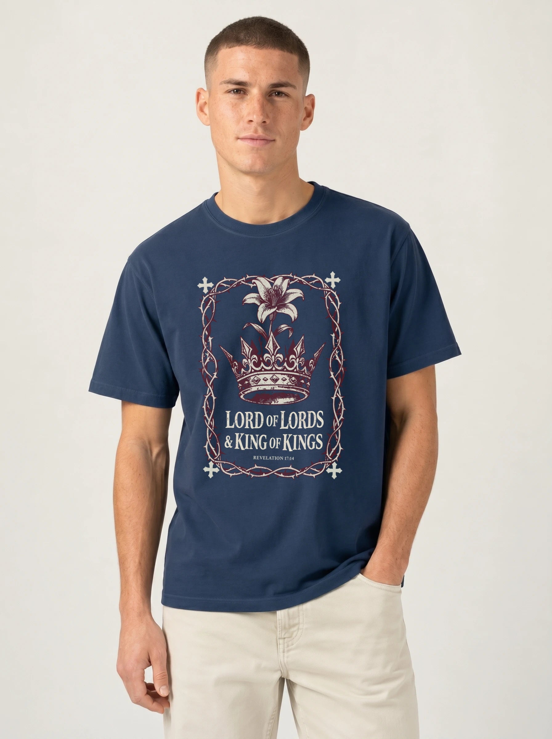 A man wearing a navy blue t-shirt with a 'Lord of the Rings: King of Kings' graphic print on the front, paired with beige pants, against a plain light gray background.