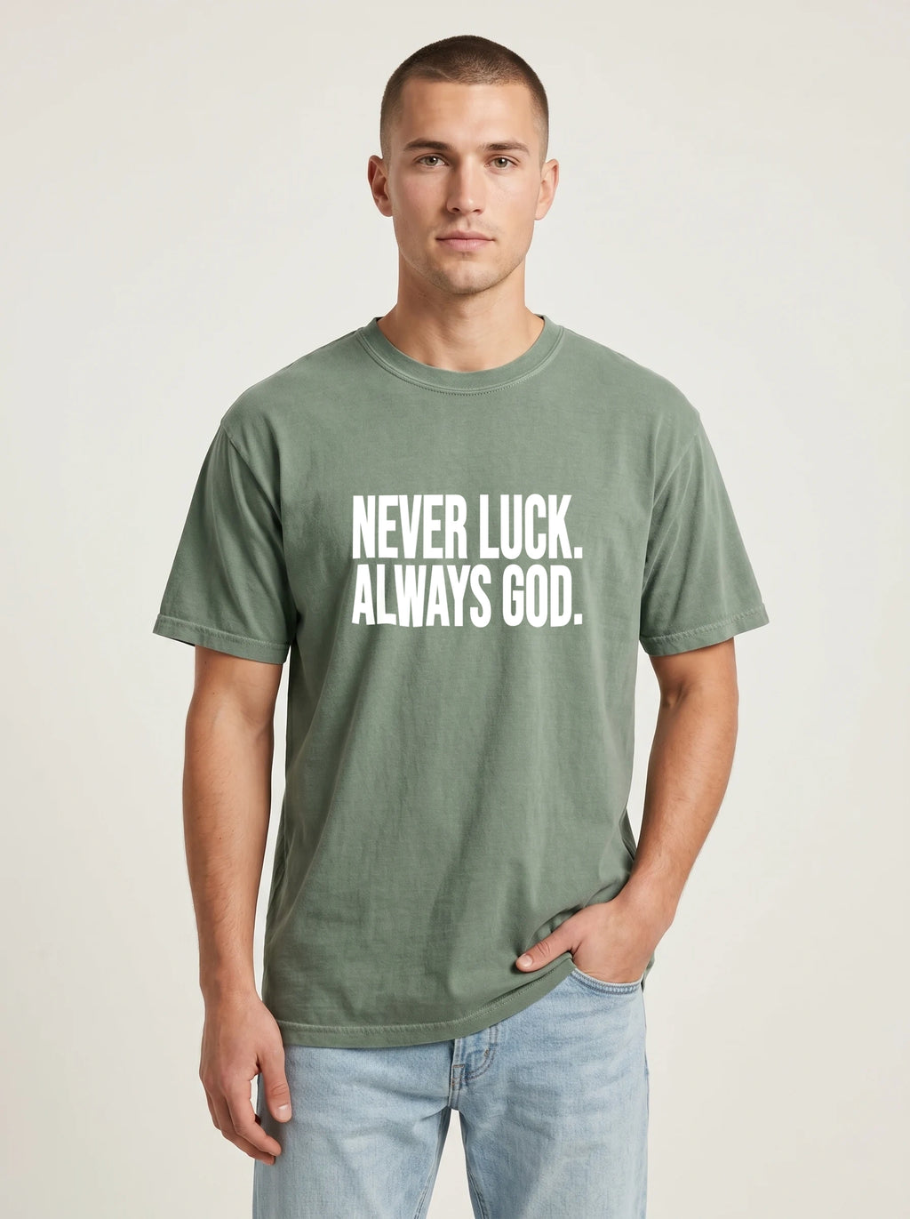 Person wearing a faded green T-shirt with white text reading “Never luck. Always God.”
