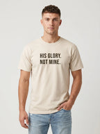 Man wearing an ivory Comfort Colors garment-dyed t-shirt printed with 'His Glory. Not Mine.' Christian faith quote