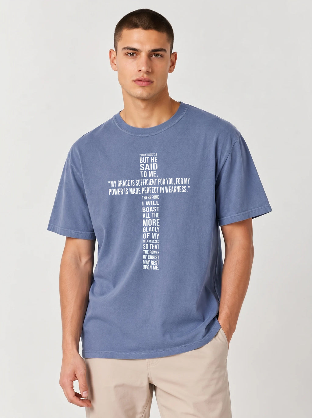 Person wearing a faded blue T-shirt with white text quoting 2 Corinthians 12:9: “My grace is sufficient for you, for my power is made perfect in weakness.”