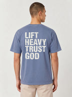 A man viewed from the back wearing a heathered blue t-shirt with distressed white text that reads 'LIFT HEAVY TRUST GOD'.