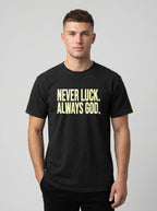 Person wearing a black T-shirt reading “Never luck. Always God.” in pale yellow lettering.