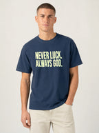 Person wearing a navy T-shirt reading “Never luck. Always God.” in pale yellow lettering.