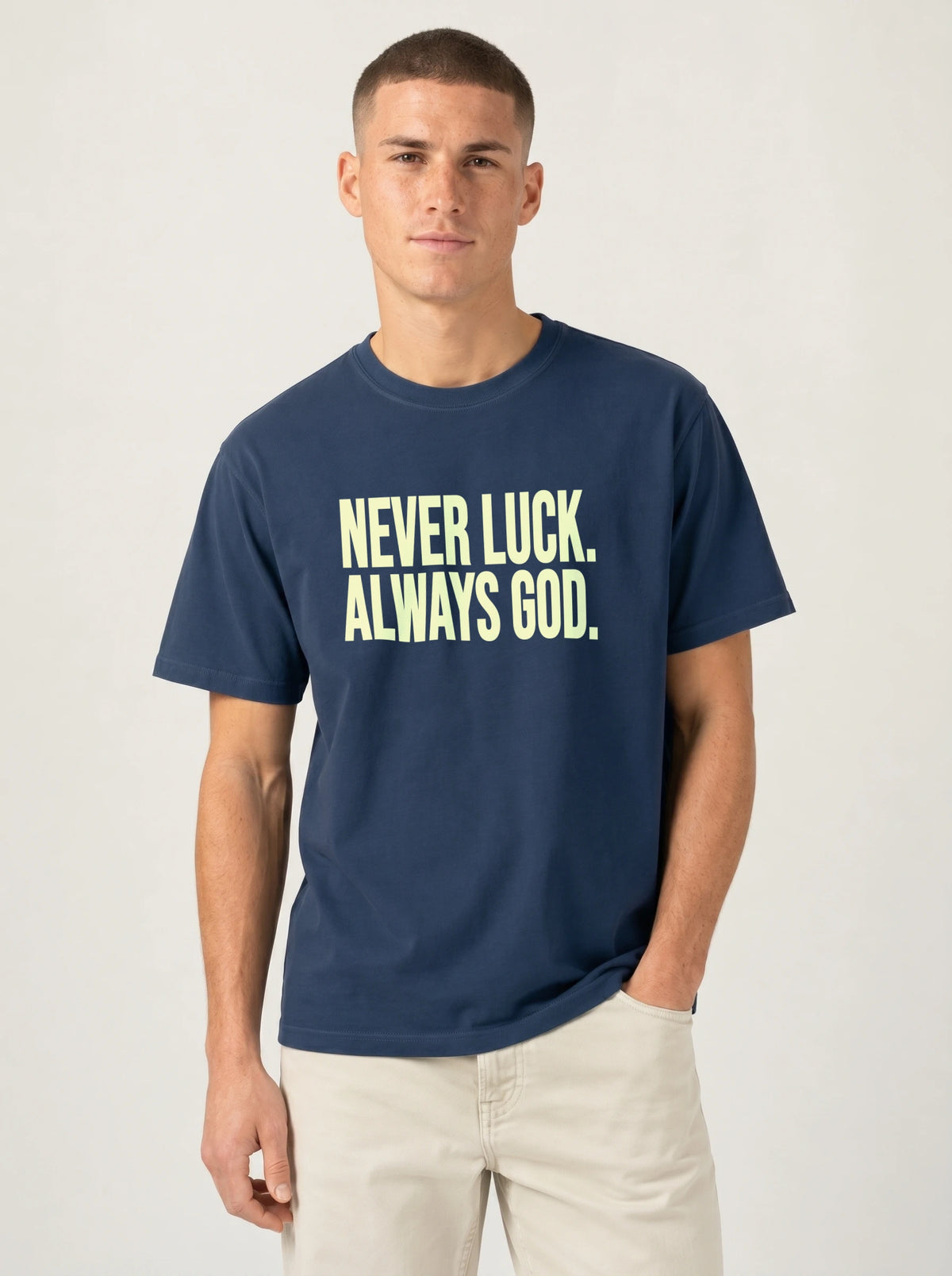 Person wearing a navy T-shirt reading “Never luck. Always God.” in pale yellow lettering.
