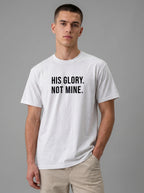 Man wearing a white Comfort Colors garment-dyed t-shirt with black print 'His Glory. Not Mine.' Christian faith quote