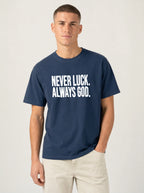 Person wearing a navy T-shirt with white text reading “Never luck. Always God.”
