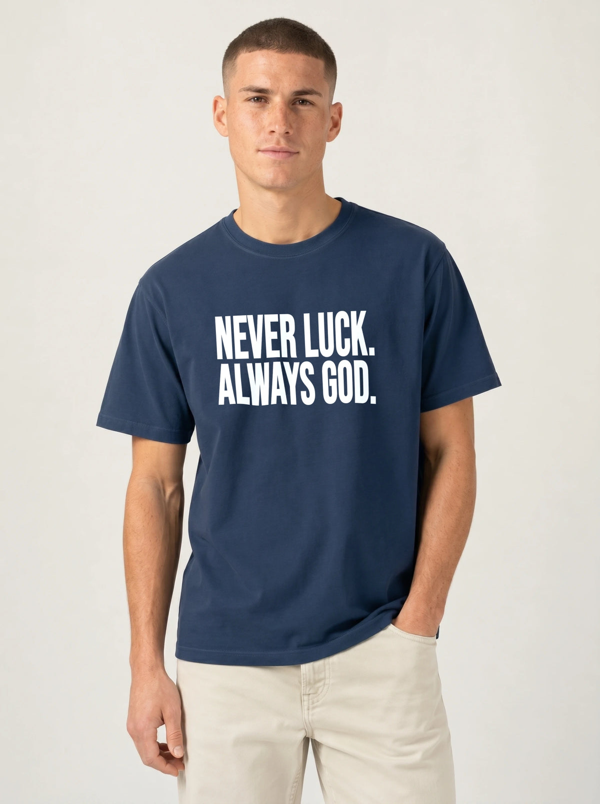 Person wearing a navy T-shirt with white text reading “Never luck. Always God.”