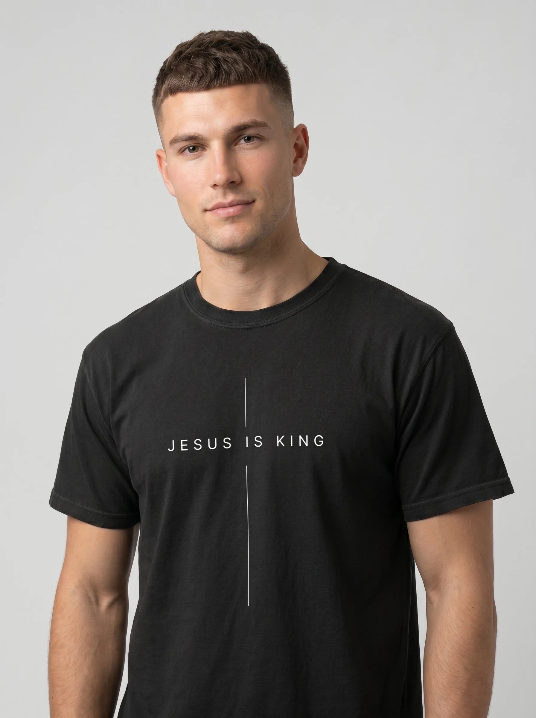 A man wearing a black crewneck t-shirt with the word 'JESUS IS KING' printed in white across the chest.