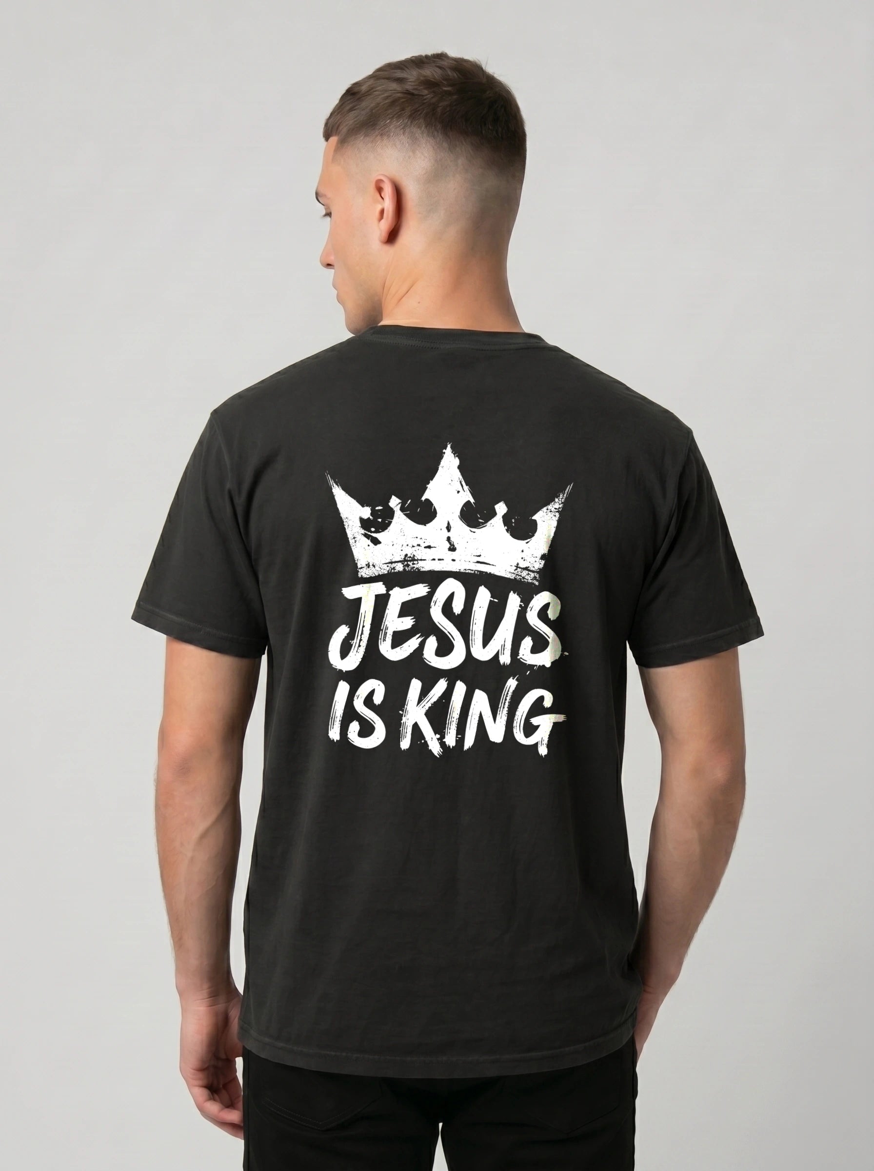 A man viewed from the back wearing a black t-shirt with a white graphic of a crown and the text 'JESUS IS KING'.