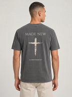 Man wearing dark gray Comfort Colors t-shirt with Made New cross graphic and 2 Corinthians 5:17 verse on back